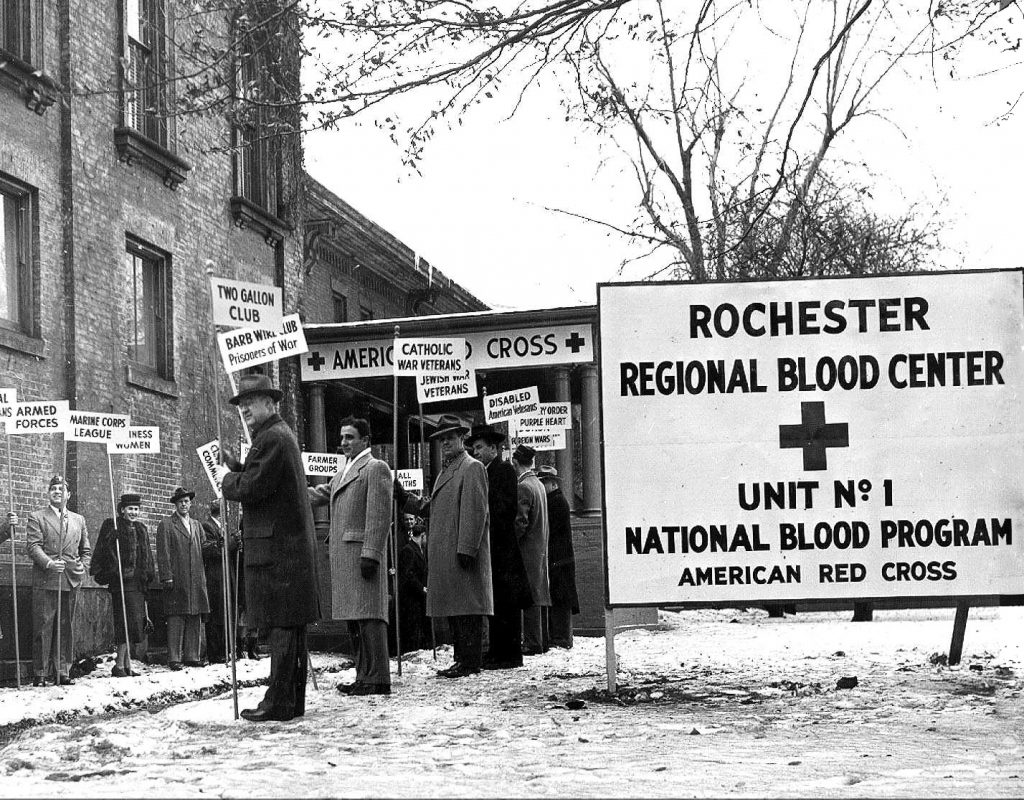 a group of people outdoors in the winter next to a sign that says Rochester Regional Blood Center Unit 01