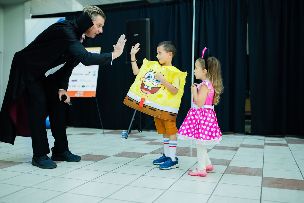 a man wearing a vampire costume high-fiving a boy wearing a Spongebob costume in the costume contest