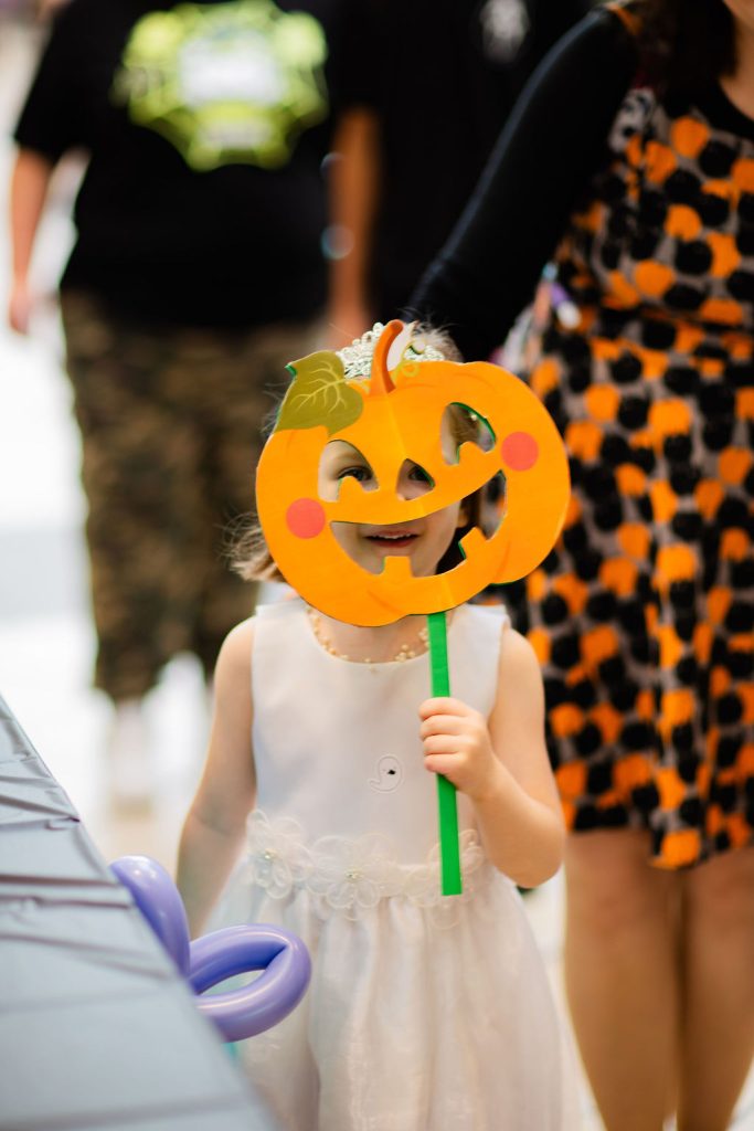 a child holding up a pumpkin face mask