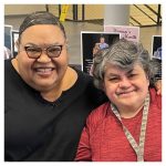 a woman with glasses and a black top sits next to a woman with short gray hair wearing a red top
