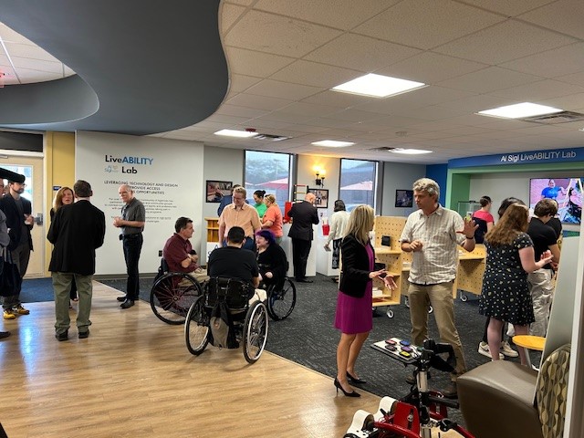 about a dozen people talking in groups amid project displays