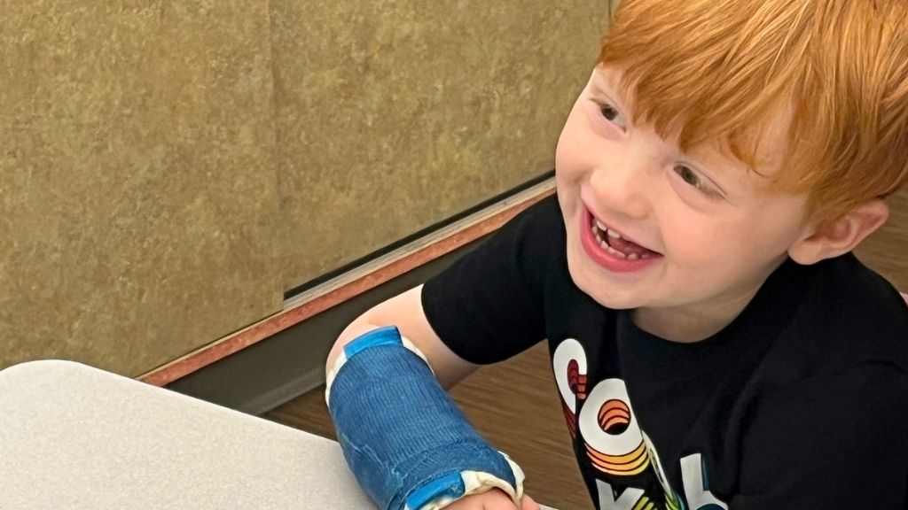 a boy with red hair and a big smile looks off to the left